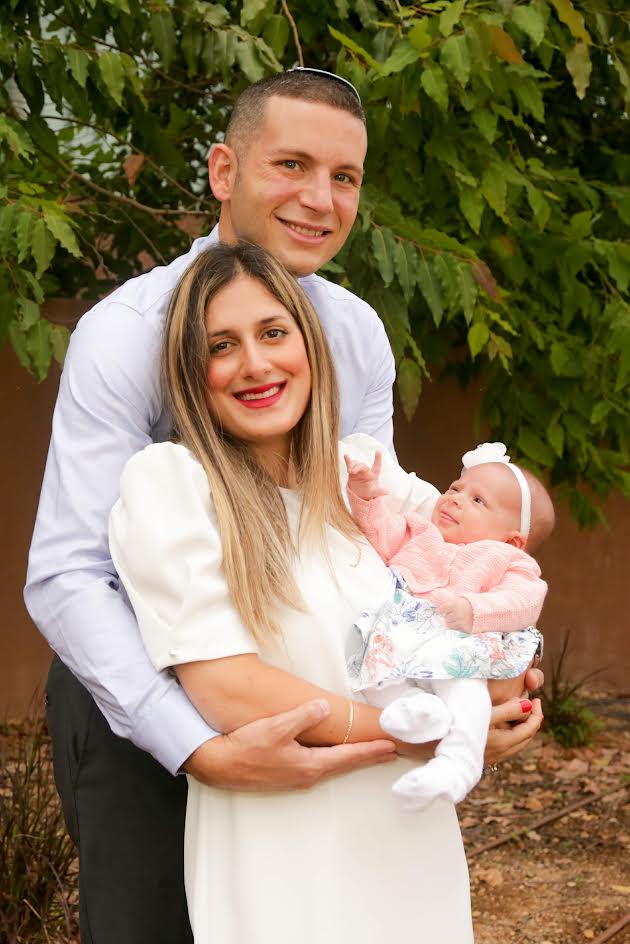Parents holding their baby daughter in pink at a family celebration