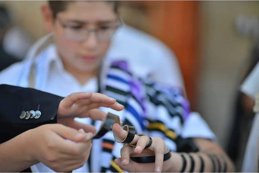 A Bar Mitzvah boy wrapping tefillin